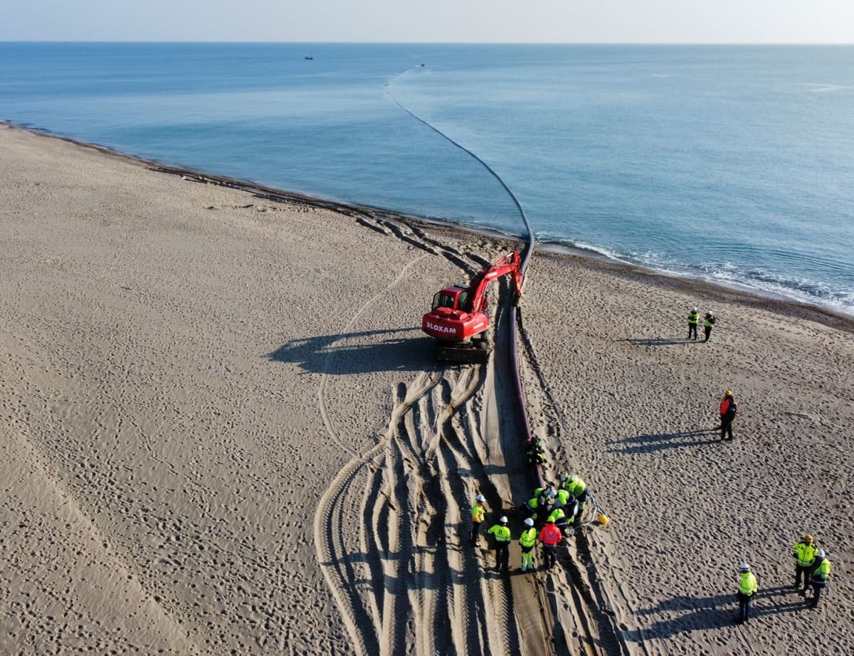 Sur la plage, une équipe procède à la mise à l'eau du fourreau.
