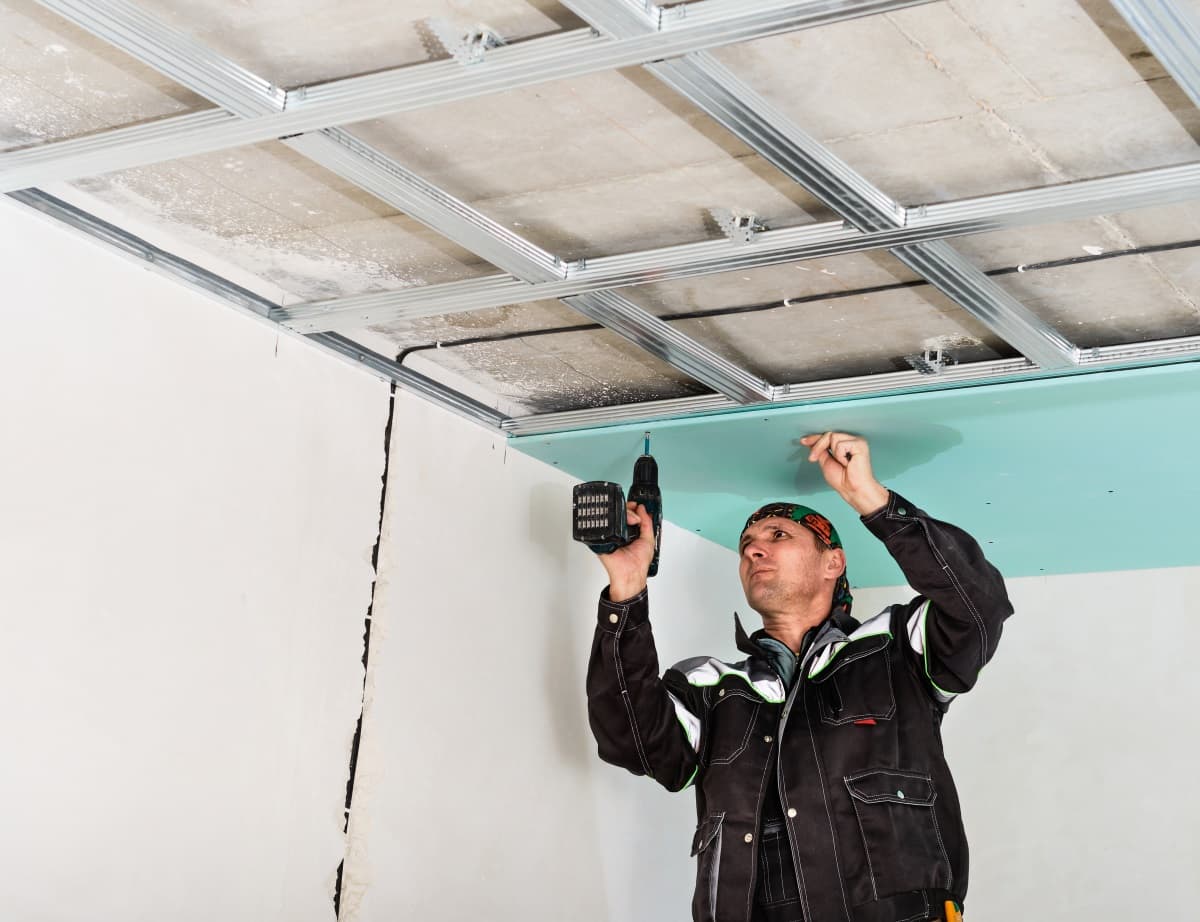 Ouvrier fixant une plaque de platre au plafond