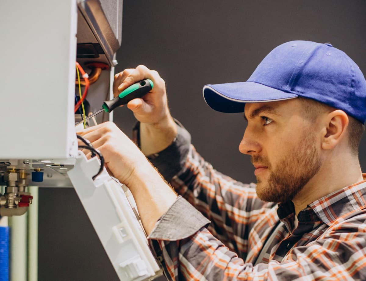 Réparateur avec un tourne vis devant une chaudière