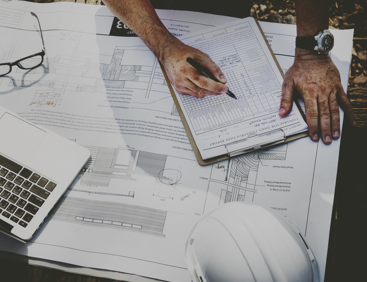 main d'un ingénieur travaillant sur des plans