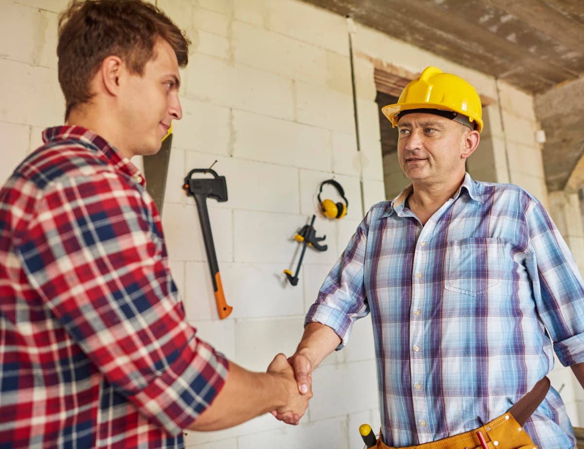 Un jeune ouvrier serre la main à un ouvrier aguerri