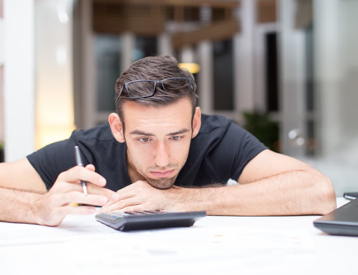 homme à l'air perplexe devant une calculatrice