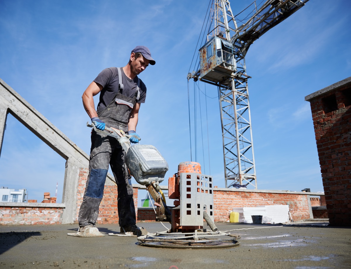 Ouvrier du btp nivelant le sol à l'aide d'une machine