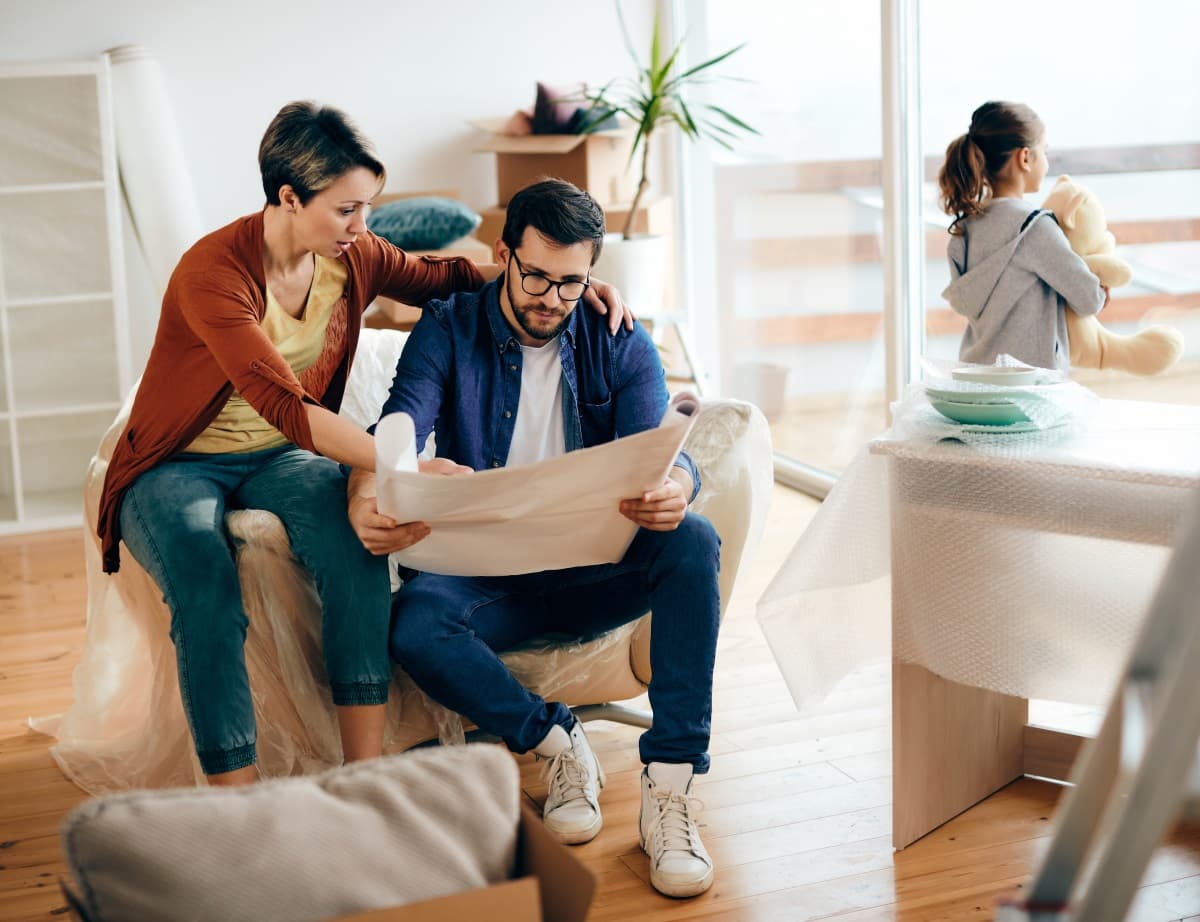 un couple avec enfant discutent de rénovation en regardant un plan de maison