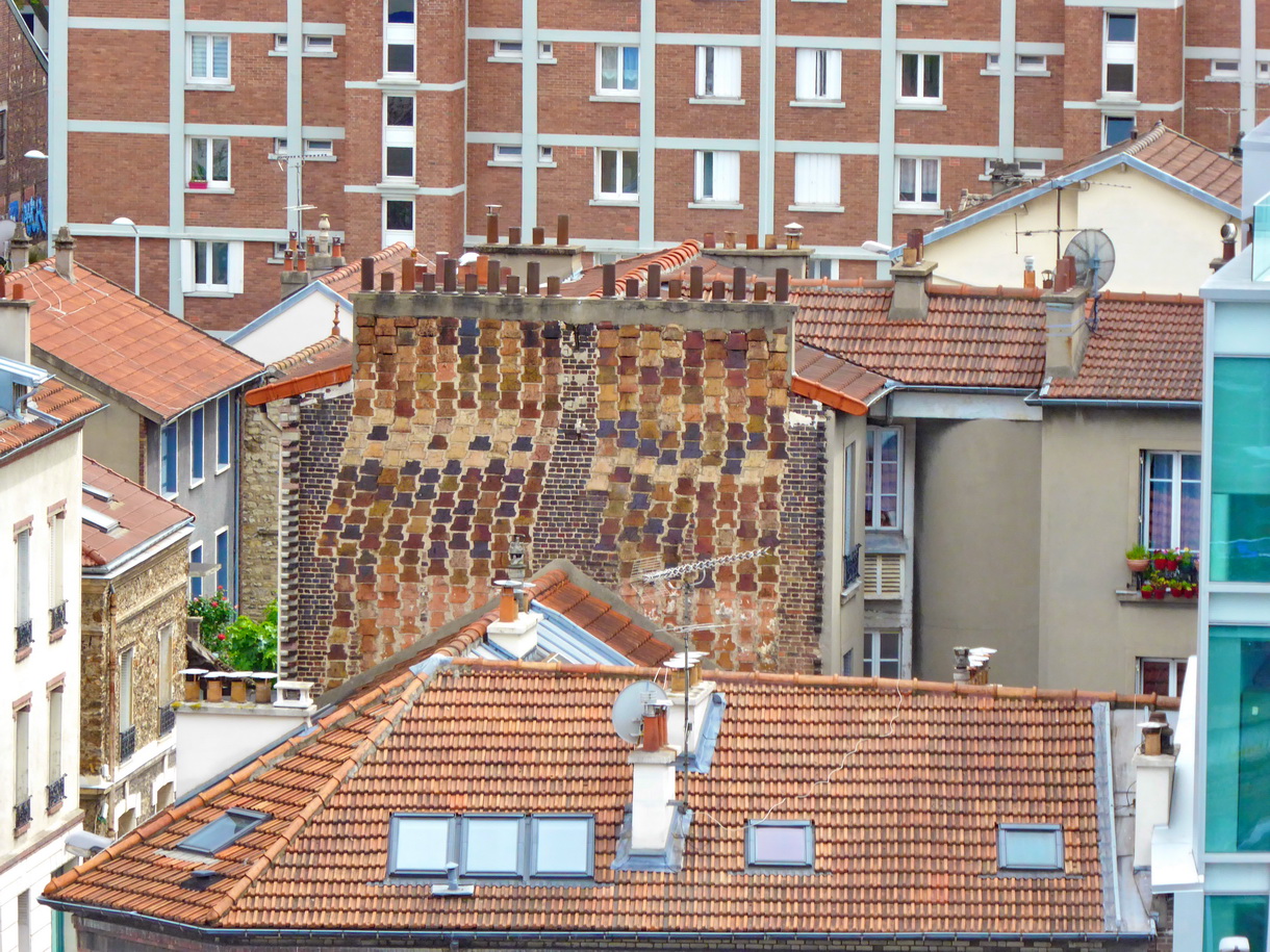 Une dizaine de boisseaux de cheminées en briques au flanc d'un bâtiment ancien