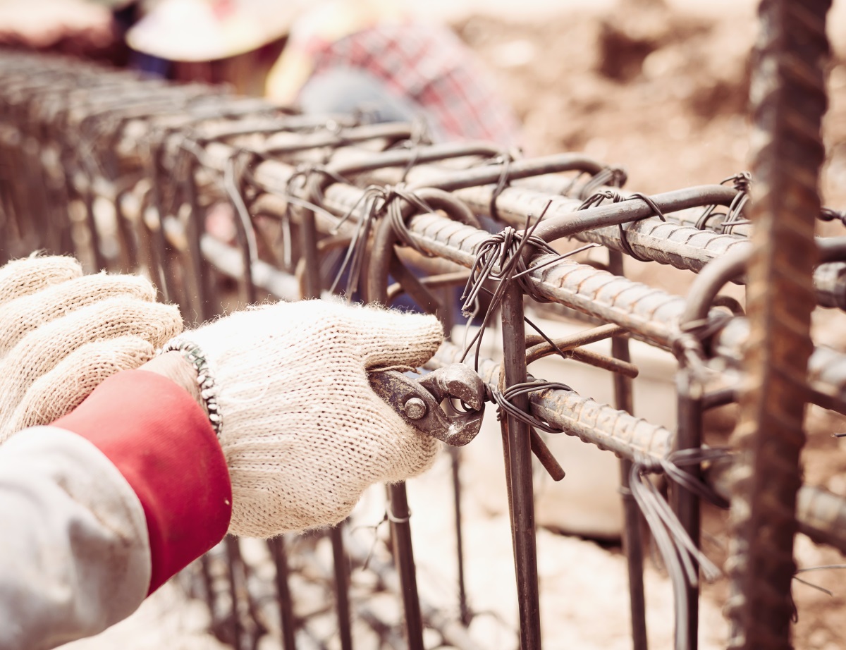 Ouvrier du bâtiment installant des tiges d'acier dans une poutre en béton armé