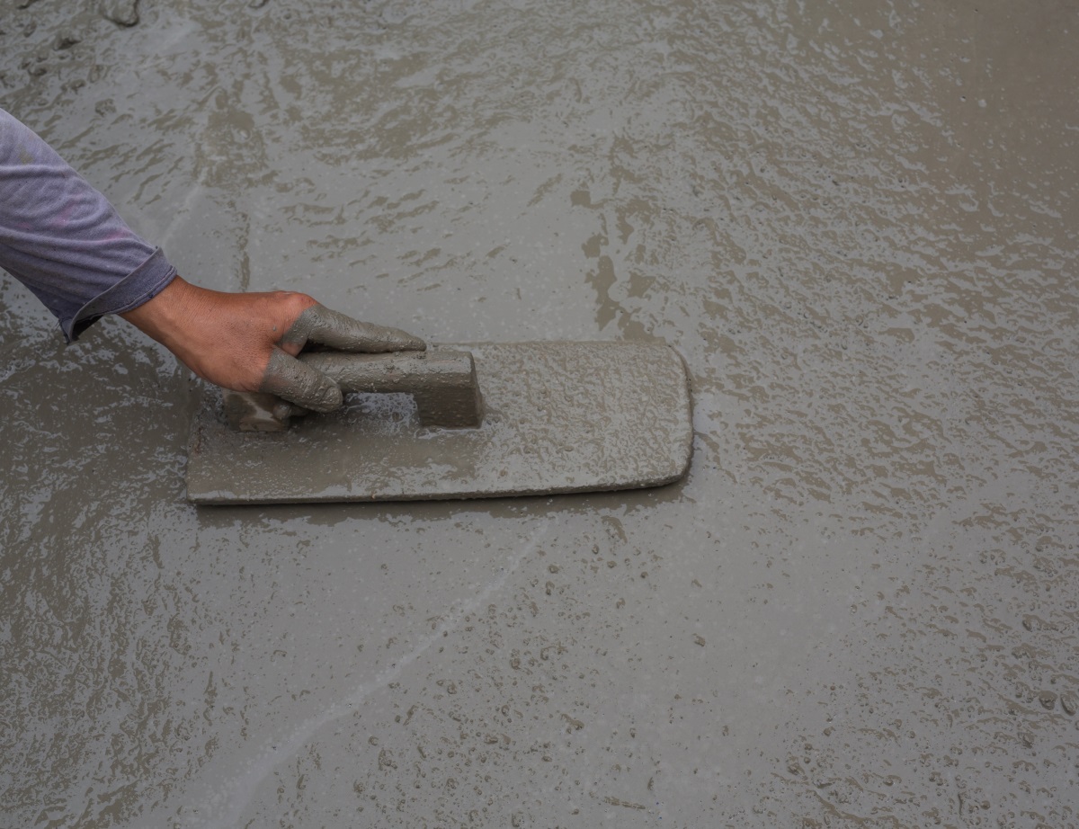 Ciment étalé par un ouvrier (gros plan sur sa main)