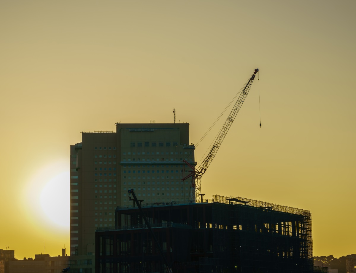 Immeuble en construction avec une grue sous le soleil couchant