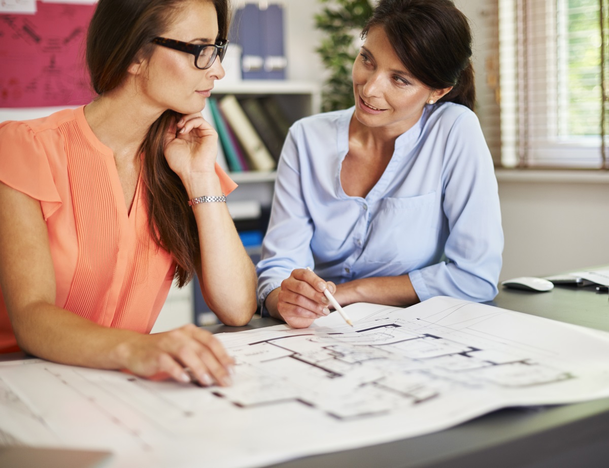 Une conseillère discute des plans d'une maison avec une femme