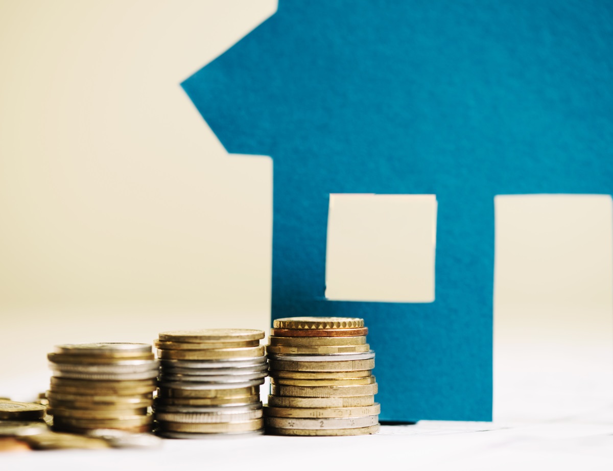 pièces de monnaies près d'une silhouette de maison