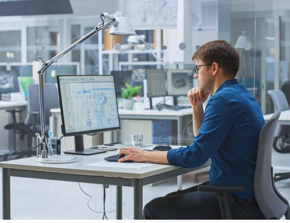 Dans un bureau, un homme travaillant sur son ordinateur avec un logiciel de configuration 3D