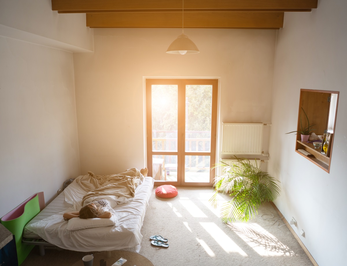 jeune femme dans son lit, dans un petit appartement
